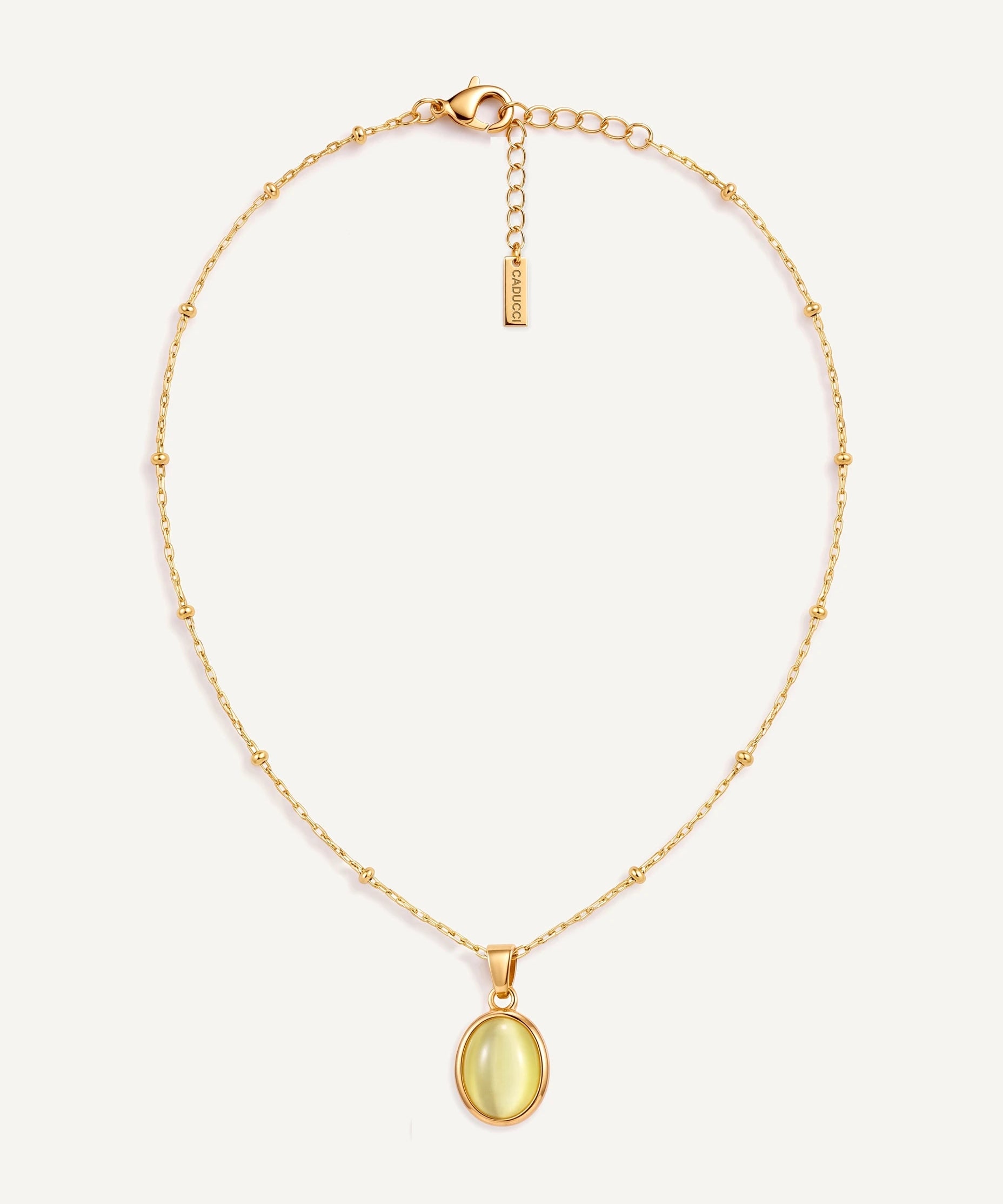 CADUCCI Capri Necklace in gold with an oval pale green cat's-eye pendant in a smooth bezel and a rectangular tag engraved with the CADUCCI logo