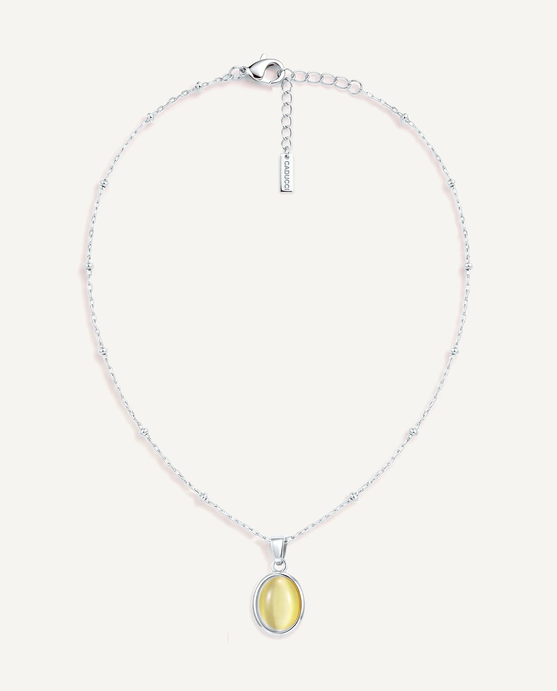 CADUCCI Capri Necklace in silver with an oval pale green cat's-eye pendant in a smooth bezel and a rectangular tag engraved with the CADUCCI logo