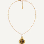 CADUCCI Luna Necklace in gold with a tiger's-eye pendant in a baroque gold frame and a rectangular tag engraved with the CADUCCI logo