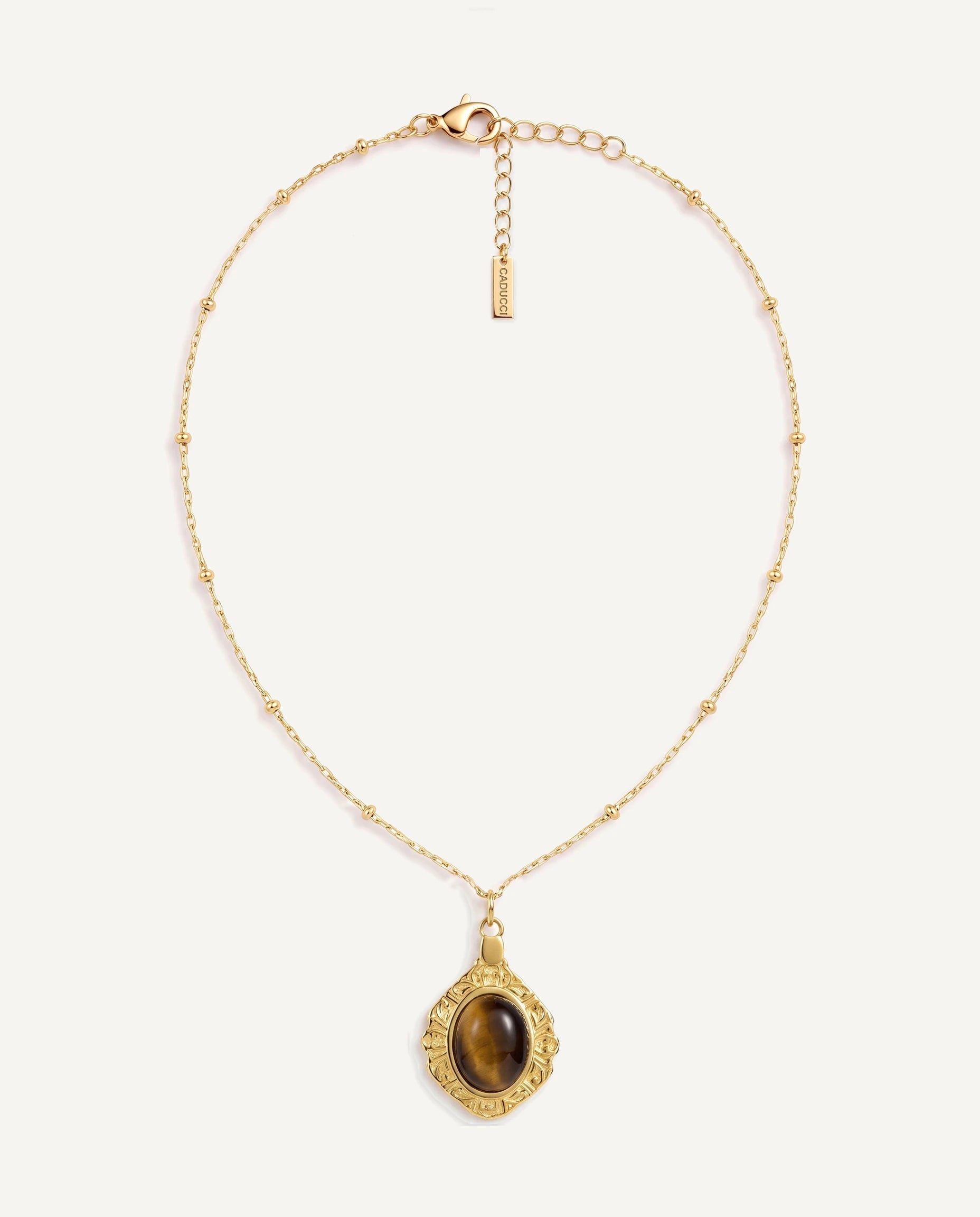 CADUCCI Luna Necklace in gold with a tiger's-eye pendant in a baroque gold frame and a rectangular tag engraved with the CADUCCI logo